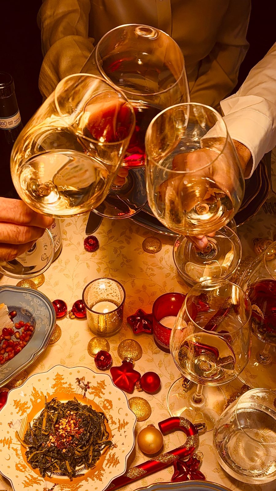 Guests raising their glasses over a candlelit holiday table